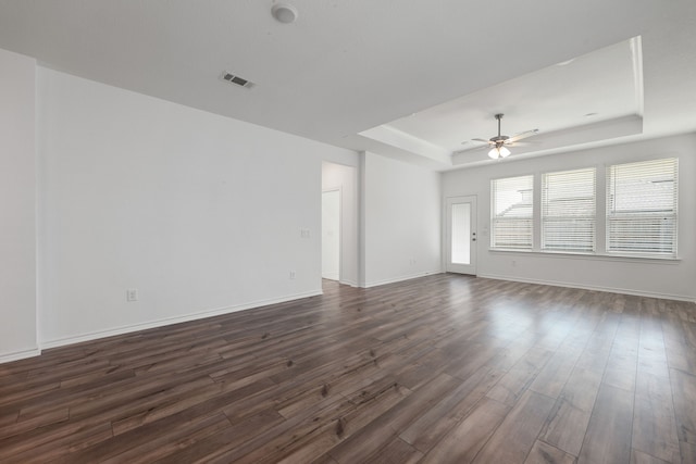 interior space with a tray ceiling, ceiling fan, and dark hardwood / wood-style floors