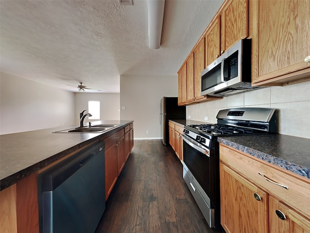 kitchen with a textured ceiling, dark hardwood / wood-style floors, appliances with stainless steel finishes, sink, and tasteful backsplash