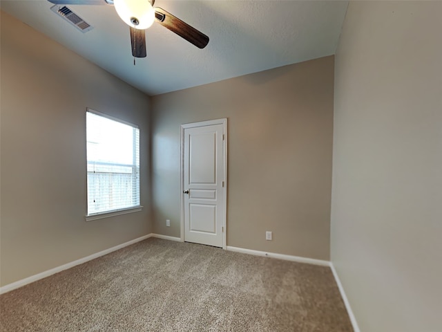 empty room featuring ceiling fan and carpet