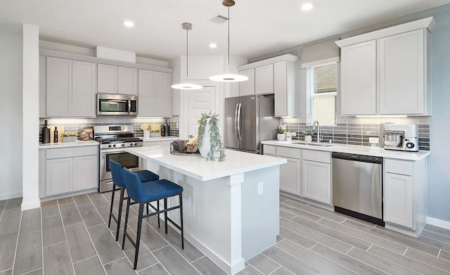 kitchen featuring white cabinets, stainless steel appliances, sink, a breakfast bar area, and a kitchen island