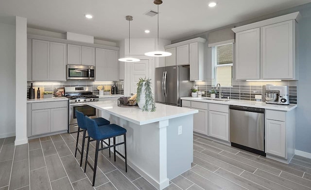 kitchen featuring a center island, stainless steel appliances, white cabinetry, sink, and a breakfast bar