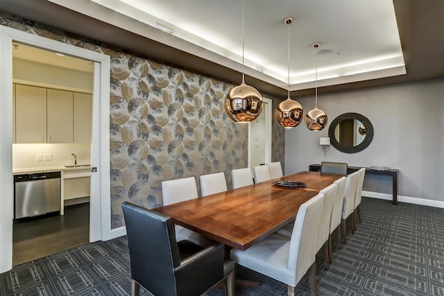 dining space with dark tile patterned flooring, a raised ceiling, and baseboards