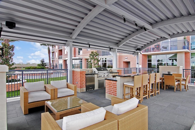 view of patio / terrace featuring a bar, an outdoor kitchen, and a grill