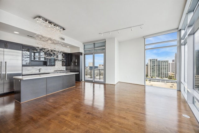 kitchen featuring stainless steel built in fridge, a kitchen island, dark hardwood / wood-style floors, and a wall of windows