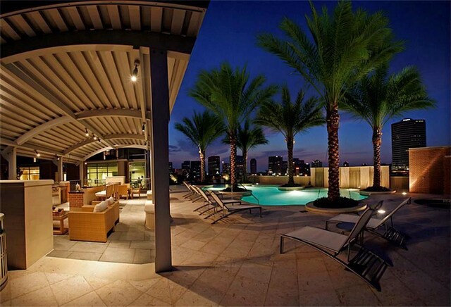 pool at dusk featuring an outdoor living space and a patio