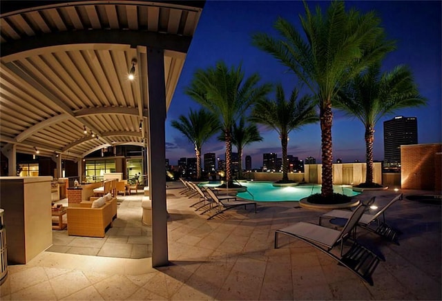 pool at dusk with a community pool and a patio