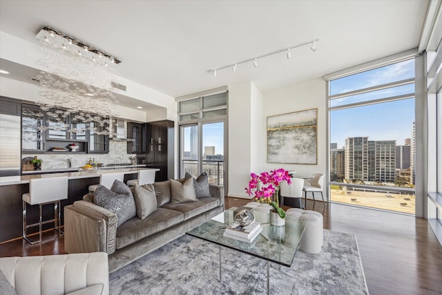 living room with a city view, wood finished floors, visible vents, expansive windows, and rail lighting