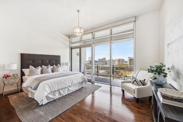 bedroom featuring dark wood-style floors, a view of city, access to exterior, and expansive windows