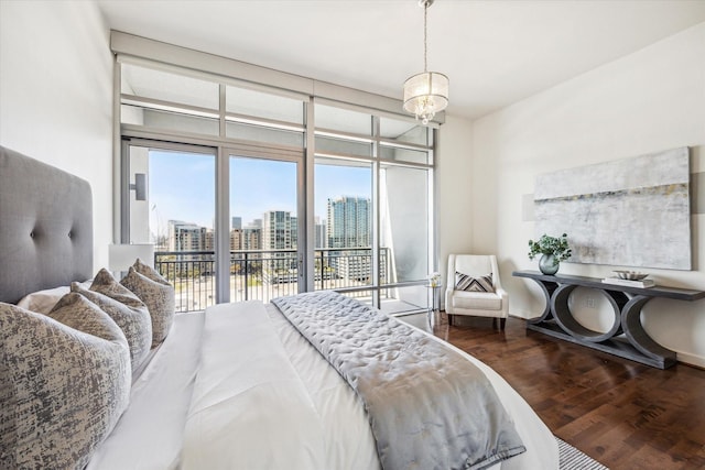 bedroom featuring a city view, wood finished floors, baseboards, access to outside, and floor to ceiling windows