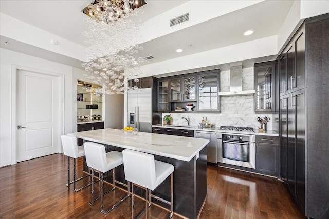 kitchen with wall chimney exhaust hood, appliances with stainless steel finishes, visible vents, and an inviting chandelier