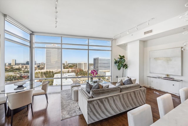 living room with a wall of windows, a city view, visible vents, and wood finished floors