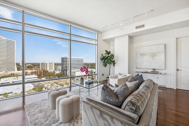 living area with visible vents, wood finished floors, expansive windows, a city view, and track lighting