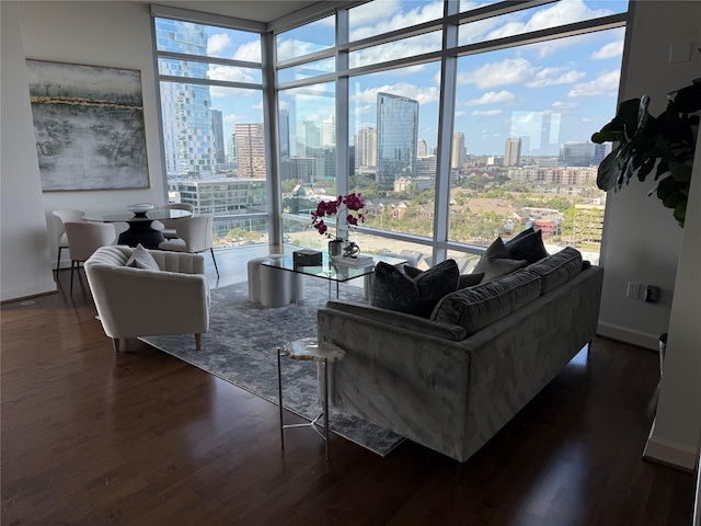 living area featuring floor to ceiling windows, a city view, dark wood finished floors, and baseboards