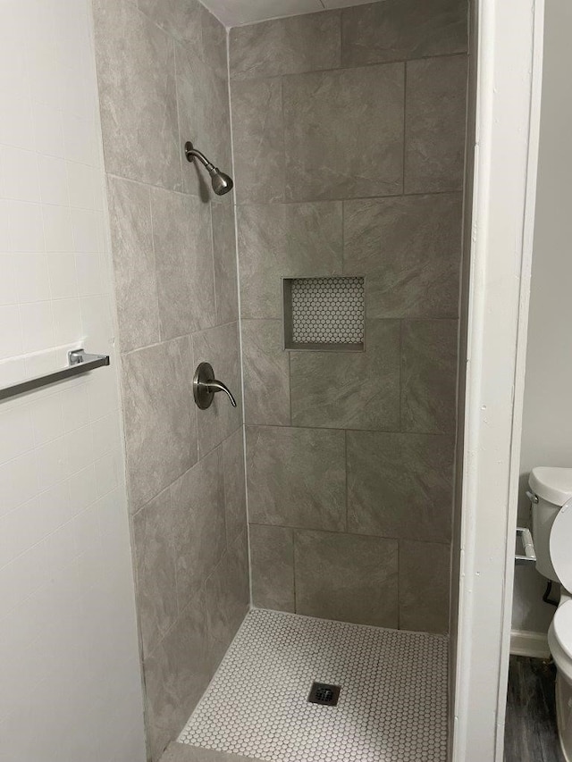 bathroom with tiled shower and toilet