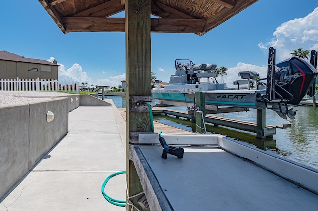 view of dock with a water view, boat lift, and fence