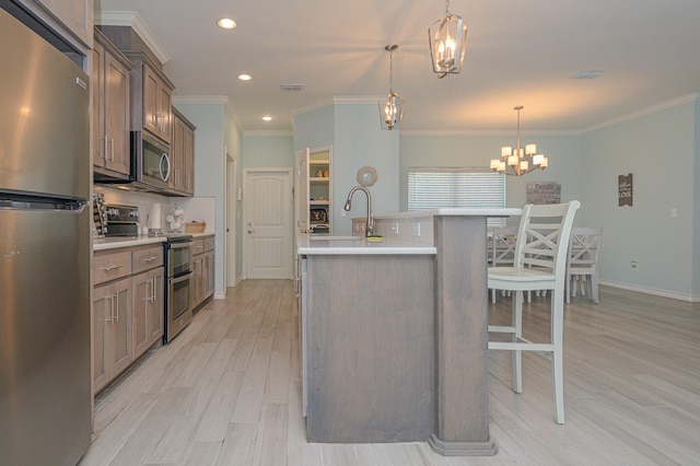 kitchen featuring stainless steel appliances, light countertops, an island with sink, and a breakfast bar area