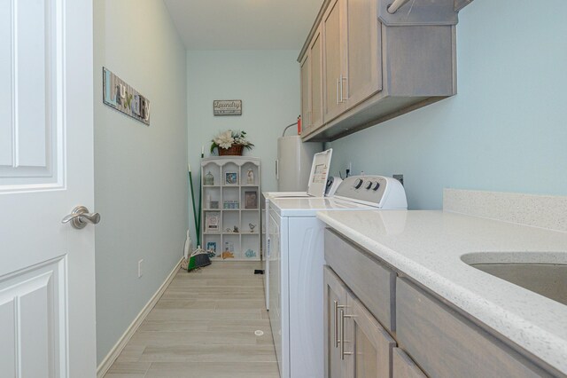 clothes washing area with cabinet space, baseboards, light wood-style floors, and independent washer and dryer