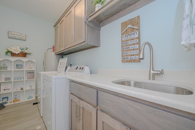 washroom featuring light wood-type flooring, cabinets, water heater, washer and dryer, and sink