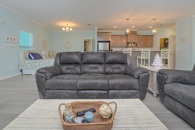 living room featuring light wood-type flooring, baseboards, a chandelier, and crown molding