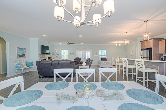 dining space featuring ceiling fan with notable chandelier, hardwood / wood-style flooring, and crown molding