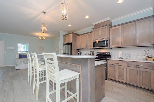 kitchen with electric stove, an island with sink, refrigerator, and hanging light fixtures