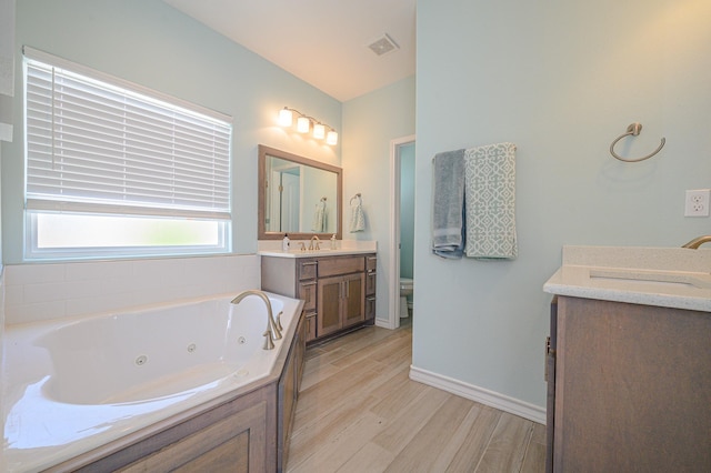 full bathroom with toilet, wood finished floors, two vanities, a sink, and visible vents