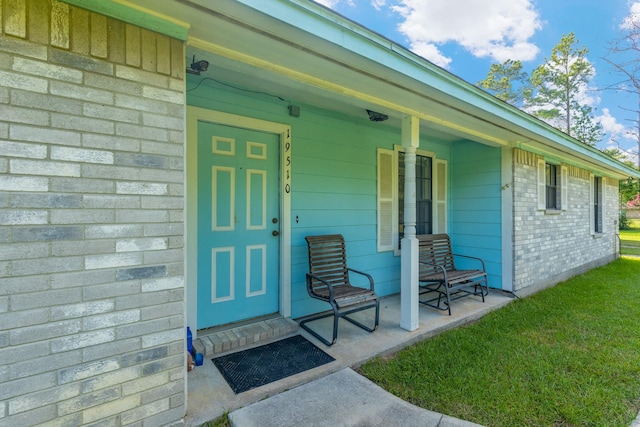 property entrance featuring a porch and a lawn