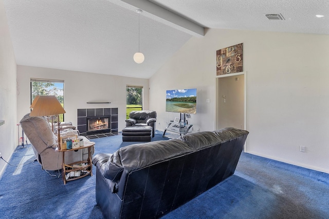 carpeted living room with a tiled fireplace, lofted ceiling with beams, and a textured ceiling