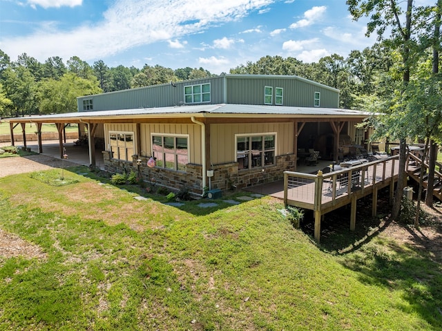 rear view of house featuring an attached carport, stone siding, driveway, and metal roof