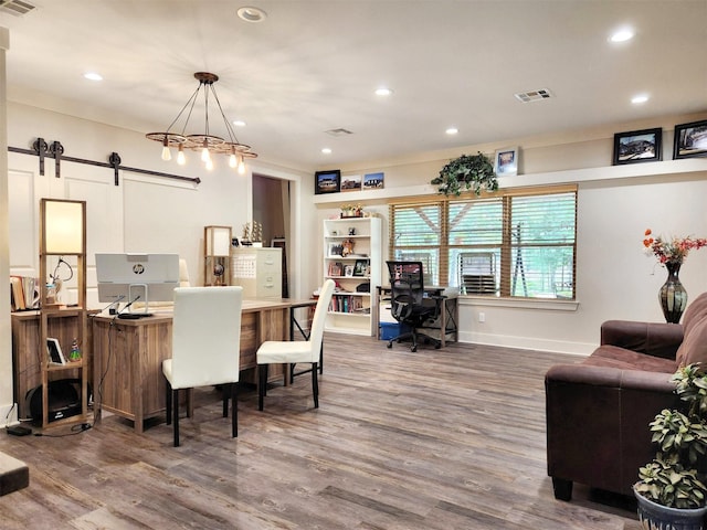 home office with recessed lighting, visible vents, a barn door, wood finished floors, and baseboards