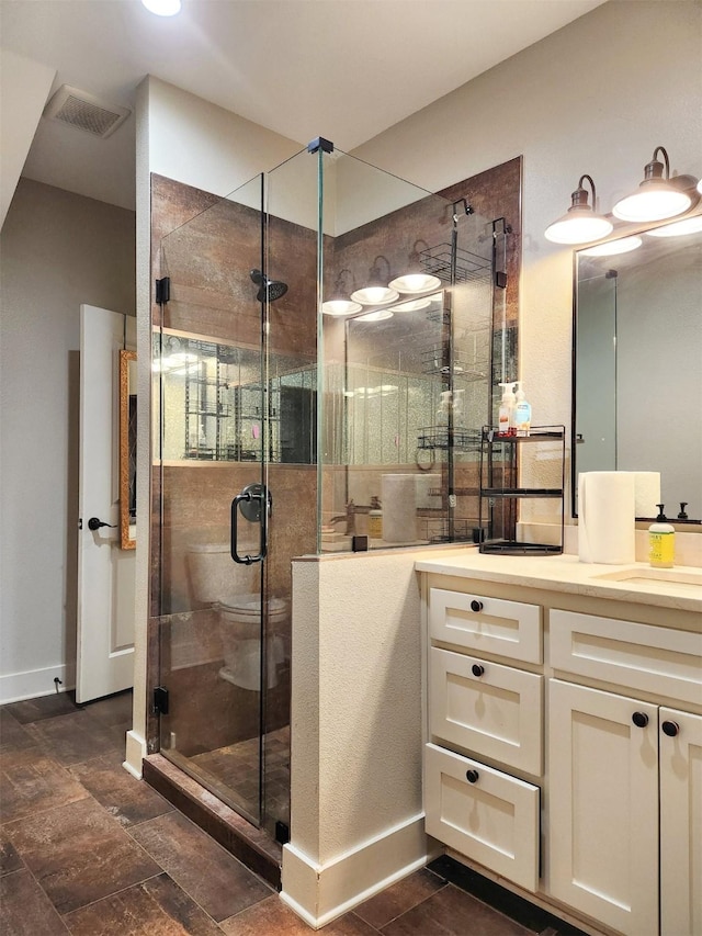 bathroom with a stall shower, visible vents, vanity, and baseboards