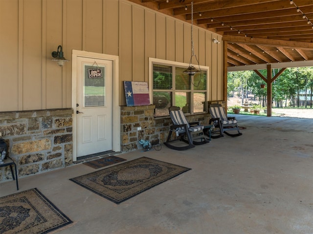 entrance to property featuring covered porch, stone siding, and board and batten siding