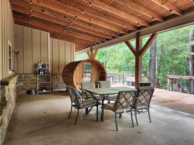 view of patio featuring a wooden deck, a view of trees, and outdoor dining space