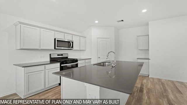 kitchen featuring a kitchen island with sink, sink, appliances with stainless steel finishes, and light hardwood / wood-style flooring