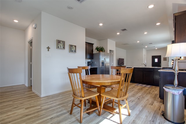 dining space with light wood-type flooring and sink