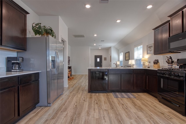 kitchen with kitchen peninsula, dark brown cabinets, black appliances, light wood-type flooring, and sink