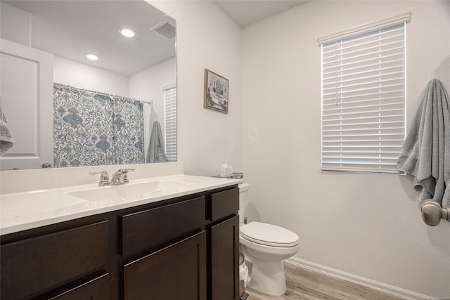 bathroom with toilet, vanity, and hardwood / wood-style flooring