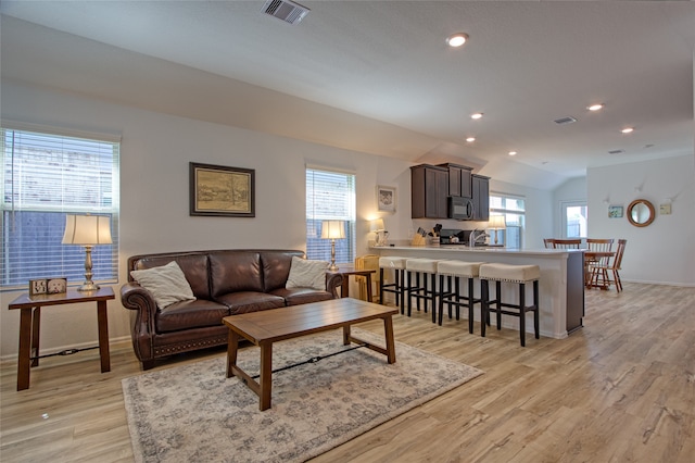 living room featuring plenty of natural light, lofted ceiling, and light hardwood / wood-style floors