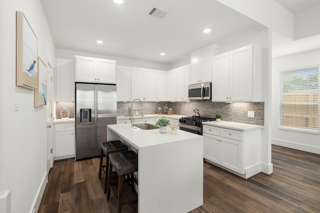 kitchen with dark wood-style floors, light countertops, visible vents, appliances with stainless steel finishes, and a sink