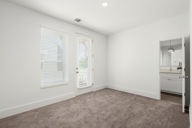 unfurnished bedroom featuring visible vents, baseboards, ensuite bath, carpet, and access to outside