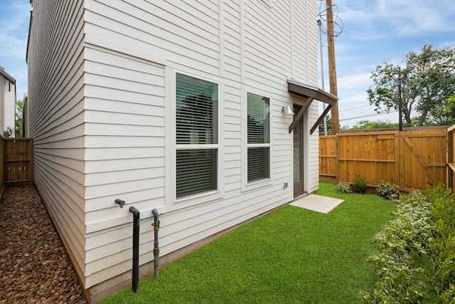 view of side of home featuring a gate, fence, and a lawn