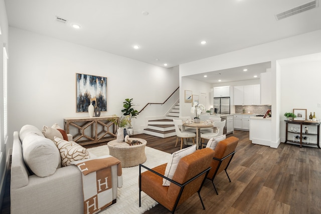 living room featuring dark wood-style floors, recessed lighting, visible vents, and stairs