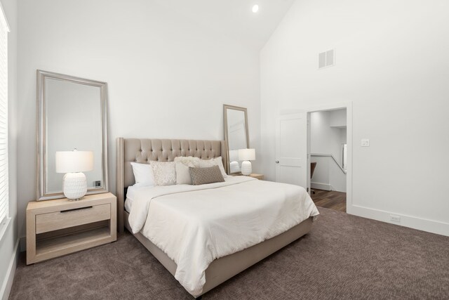 bedroom with dark colored carpet and high vaulted ceiling