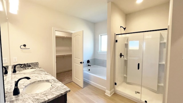 bathroom with wood finished floors, a shower stall, a bath, and a sink
