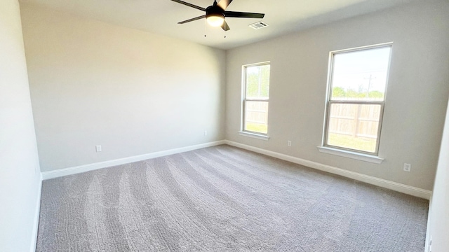 carpeted spare room with baseboards, visible vents, and ceiling fan