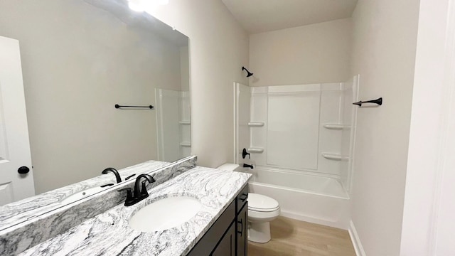 full bath with wood finished floors, baseboards, toilet, shower / washtub combination, and vanity