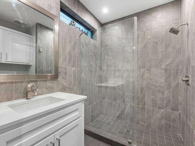 bathroom featuring tile walls, tiled shower, and vanity