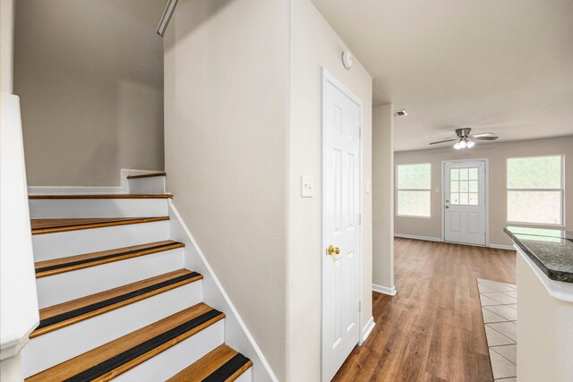 stairs featuring ceiling fan and hardwood / wood-style floors