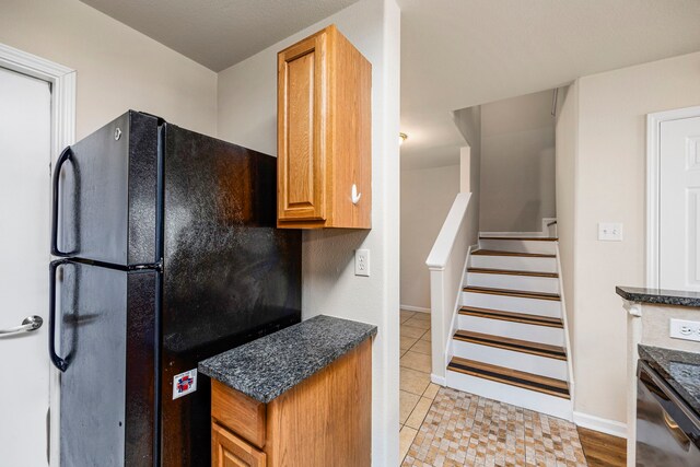 kitchen with dishwasher, light tile patterned floors, and black fridge