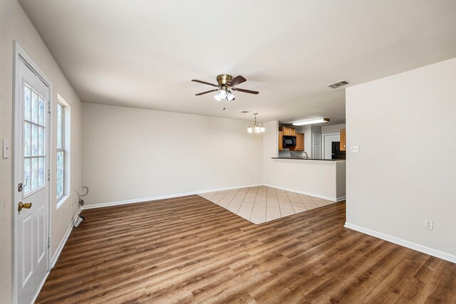 unfurnished living room with wood-type flooring and ceiling fan with notable chandelier